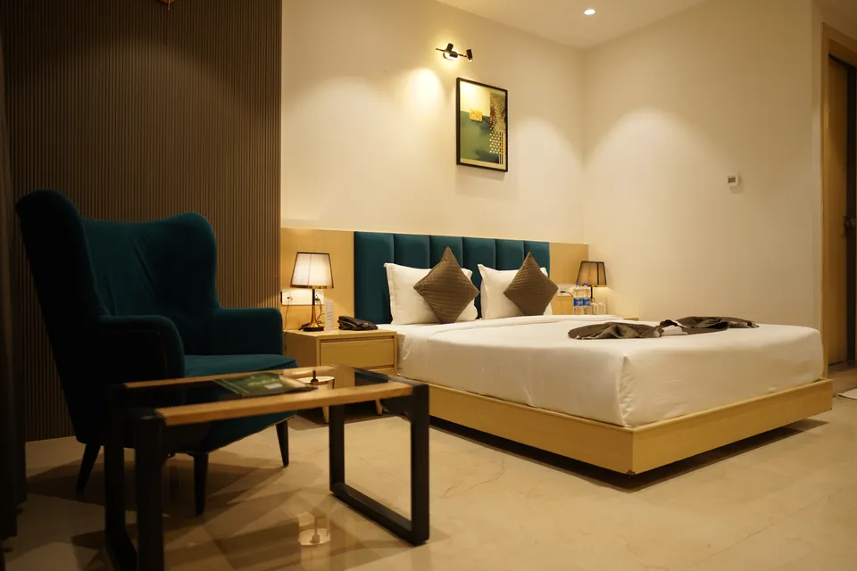Suite bedroom with a king-size bed and teal wingback chair